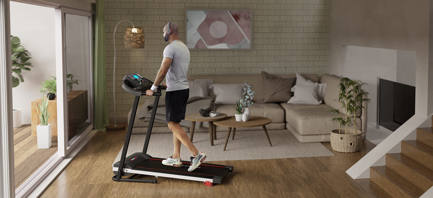 Schwarzes Laufband F10 Sportstech Mann läuft in Sportkleidung mit Kopfhörern auf schwarzem Laufband F10 im Wohnzimmer